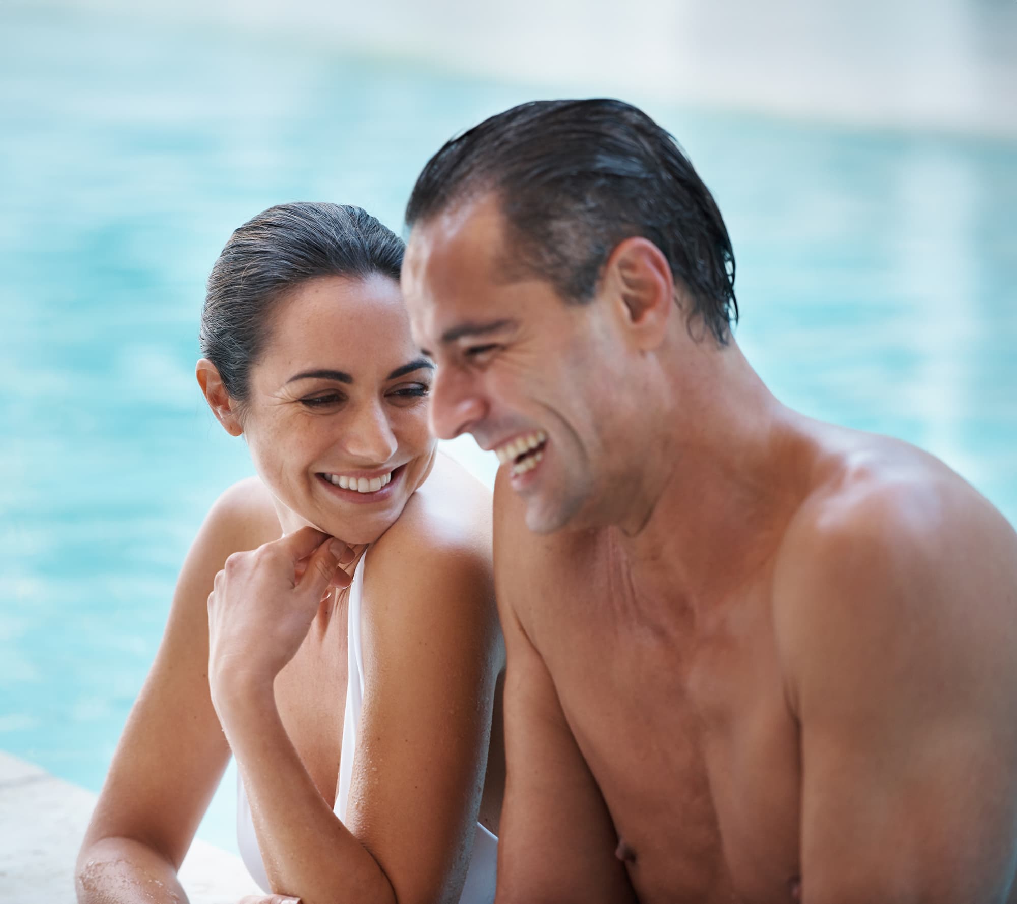 Man and woman hanging out in pool amenity features laughing at Livana Fair Lawn